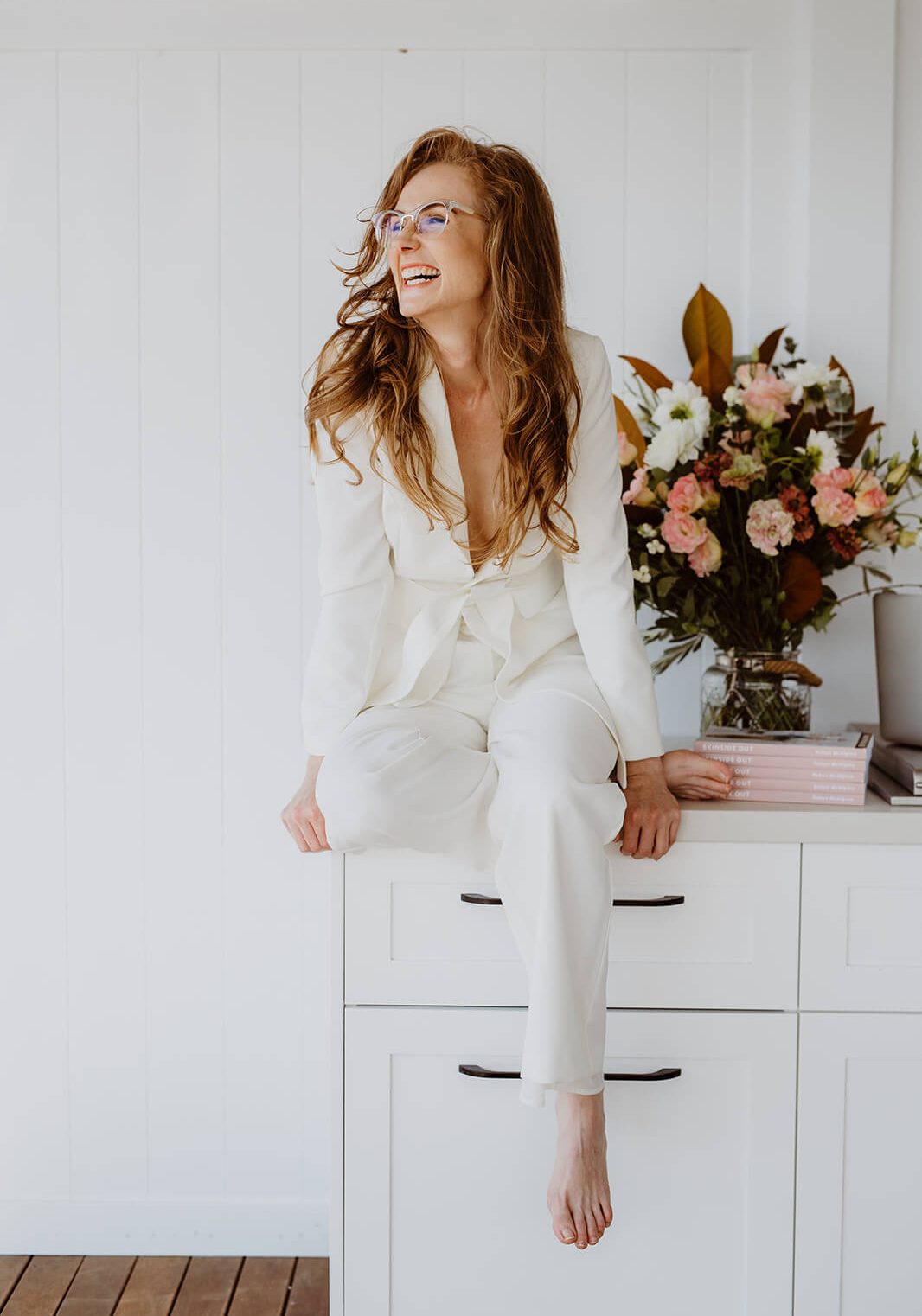 Robyn in a personal branding photography session sitting on drawers with flowers in background